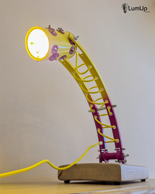 Lampada artigianale realizzata con parti di ruota di bicicletta e legno di recupero.
Colore Giallo e viola - Cavo tessile giallo - Braccio inclinabile - Punto luce snodato - immagine intera