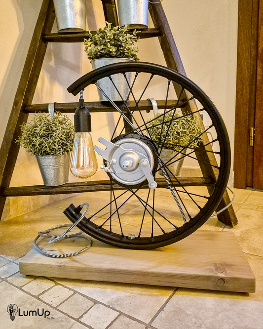 Lampada artigianale realizzata con ruota di motocicletta e legno di recupero.
Colore Nero - Lampadina stile vintage - Cavo elettrico bianco e nero - immagine intera