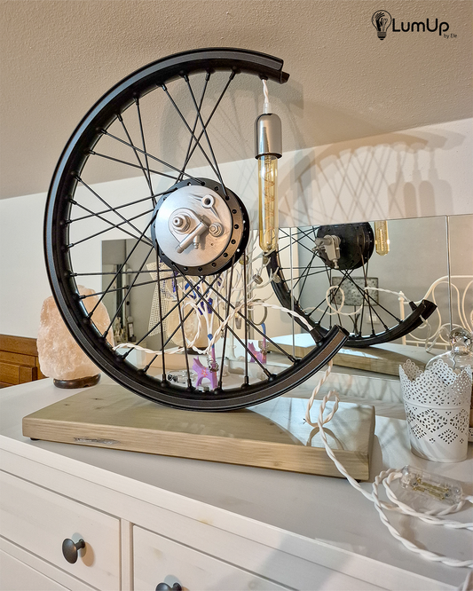 Lampada artigianale realizzata con ruota di motocicletta e legno di recupero.
Colore Nero - Lampadina stile vintage - Cavo elettrico bianco trecciato - immagine intera