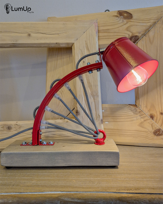 Lampada artigianale realizzata con parte di ruota di bicicletta e legno di recupero.
Colore Rosso - Cavo tessile bianco e nero - Punto luce snodato - immagine intera