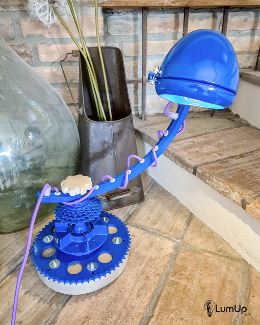 Lampada artigianale realizzata con parti di ruota di bicicletta e legno di recupero.
Colore Blu - Cavo tessile viola - Braccio rotante - Punto luce snodato - immagine intera
