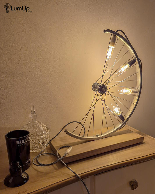 Lampada artigianale realizzata con ruota di bicicletta e legno di recupero.
Colore Argento - Lampadine stile vintage - Cavo elettrico bianco e nero - immagine intera