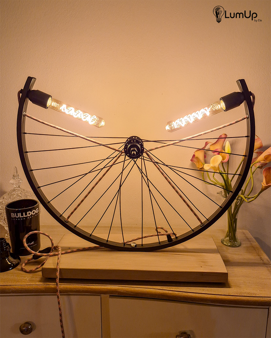 Lampada artigianale realizzata con ruota di bicicletta e legno di recupero.
Colore Nero - Lampadine stile vintage - Cavo elettrico rosa e salvia - immagine intera