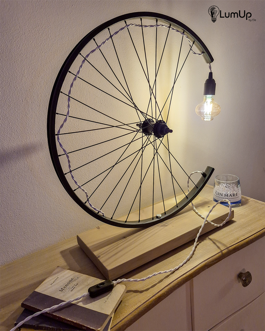 Lampada artigianale realizzata con ruota di bicicletta e legno di recupero.
Colore Nero - Lampadina stile vintage - Cavo elettrico bianco trecciato - immagine intera