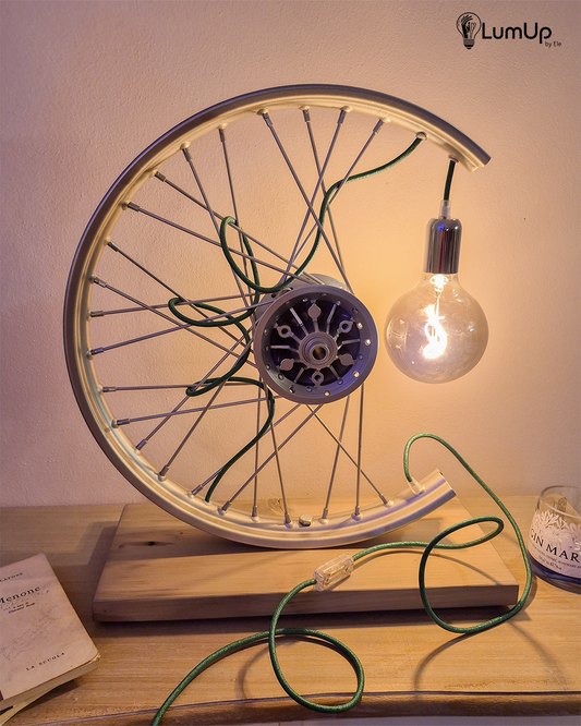Lampada artigianale realizzata con ruota di motocicletta e legno di recupero.
Colore Argento - Lampadina stile vintage - Cavo elettrico verde - immagine intera