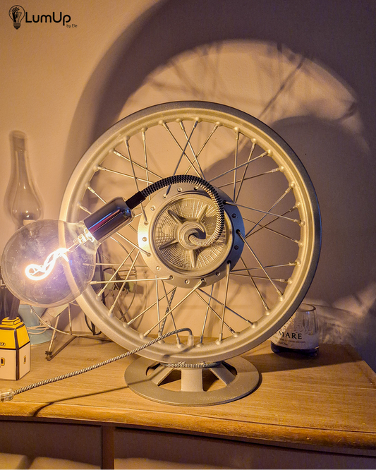 Lampada artigianale realizzata con ruota di motocicletta e base metallica.
Colore Argento - Lampadina stile vintage - Braccio modellabile - Cavo elettrico bianco e nero - immagine intera