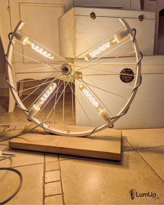 Lampada artigianale realizzata con ruota di bicicletta e legno di recupero.
Colore Bianco - Lampadine stile vintage - Cavo elettrico bianco e nero - immagine intera