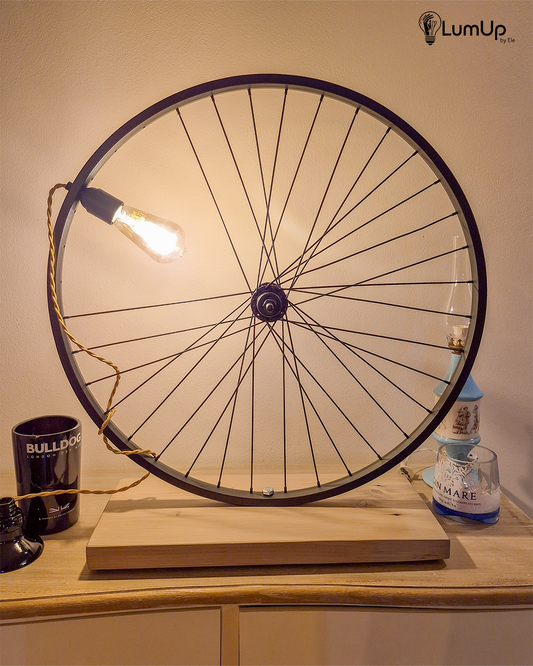 Lampada artigianale realizzata con ruota di bicicletta e legno di recupero.
Colore Nero - Lampadina stile vintage - Cavo elettrico oro trecciato - immagine intera